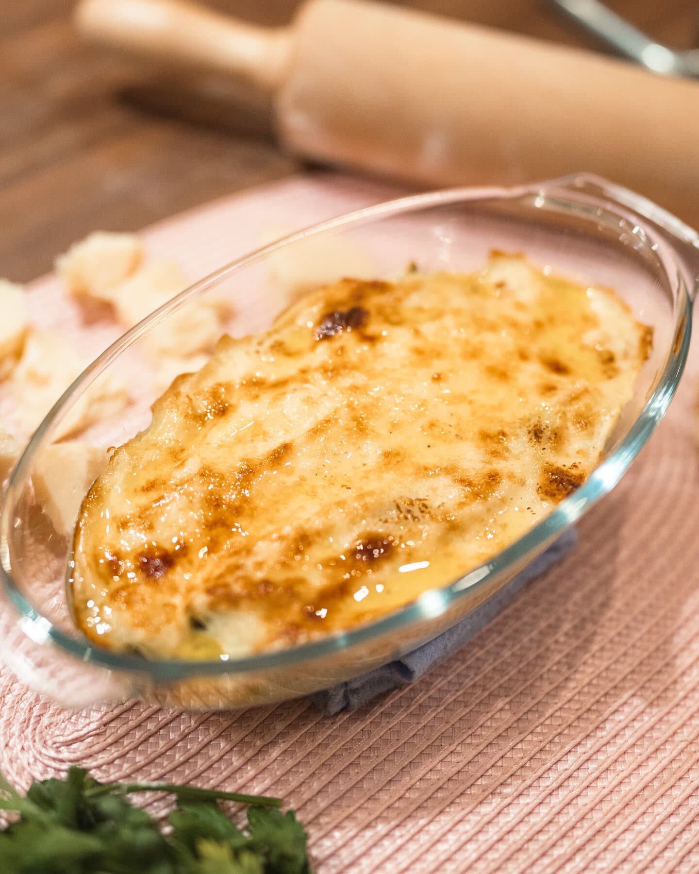 Les cannelloni gratinés dans leur plat en verre, le rouleau à pâtisserie derrière