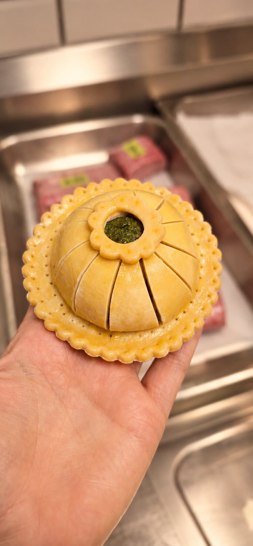 Un pithivier doré, la pâte ciselée en pétales, posé dans la main
