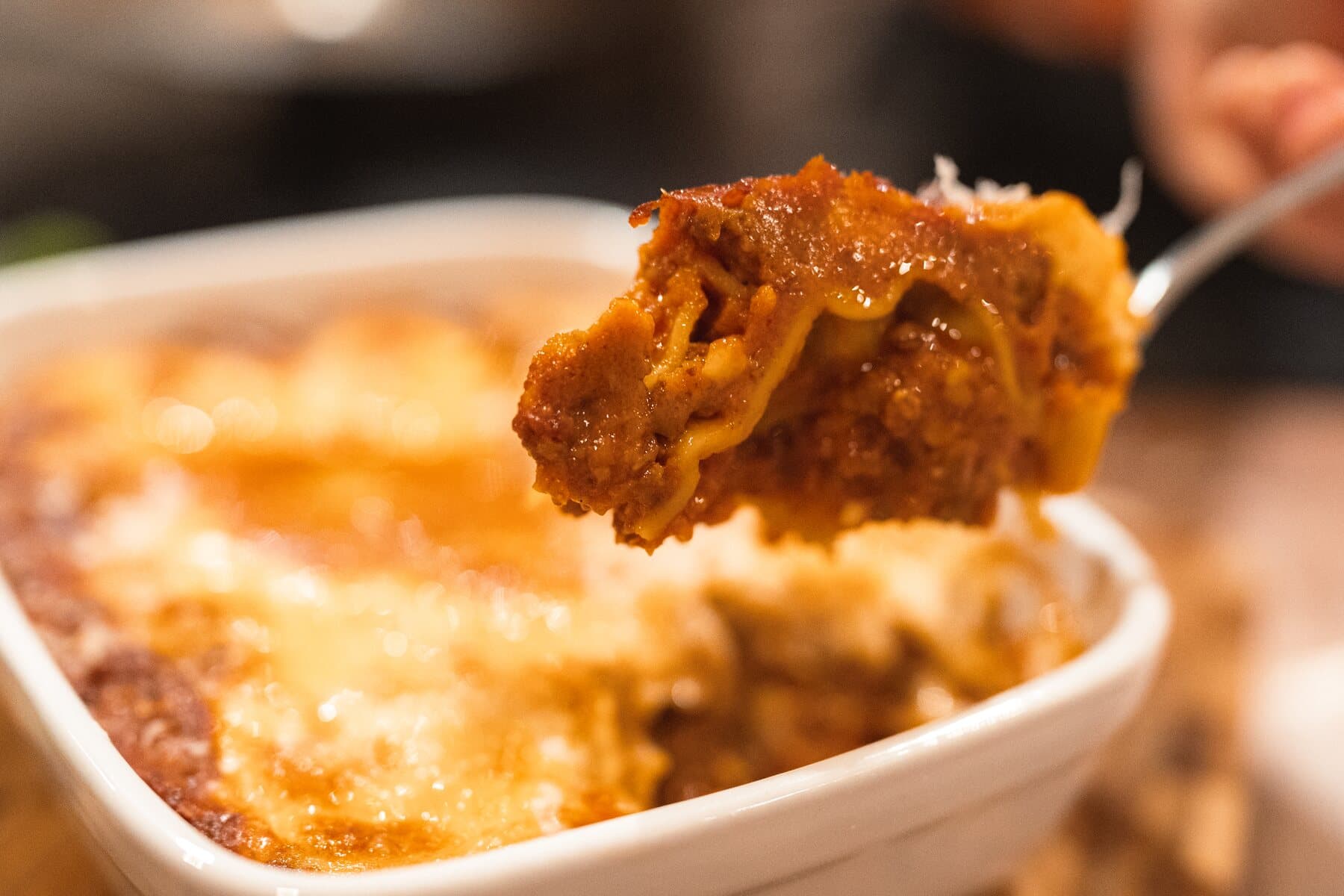 Une part de lasagne soulevée du plat, le ragù entre les feuilles de pasta
