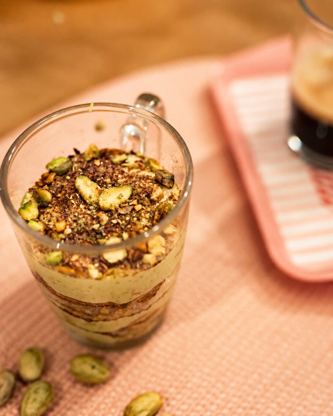 Le tiramisù à la pistache dans sa tasse en verre, des pistaches tout autour