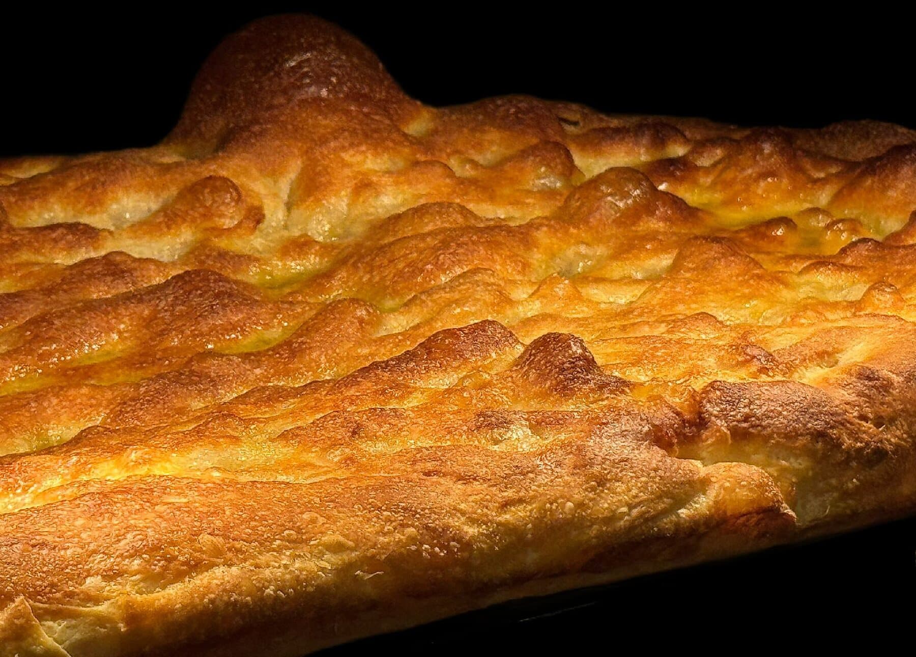 Une focaccia dorée et gonflée, vue de près à la sortie du four