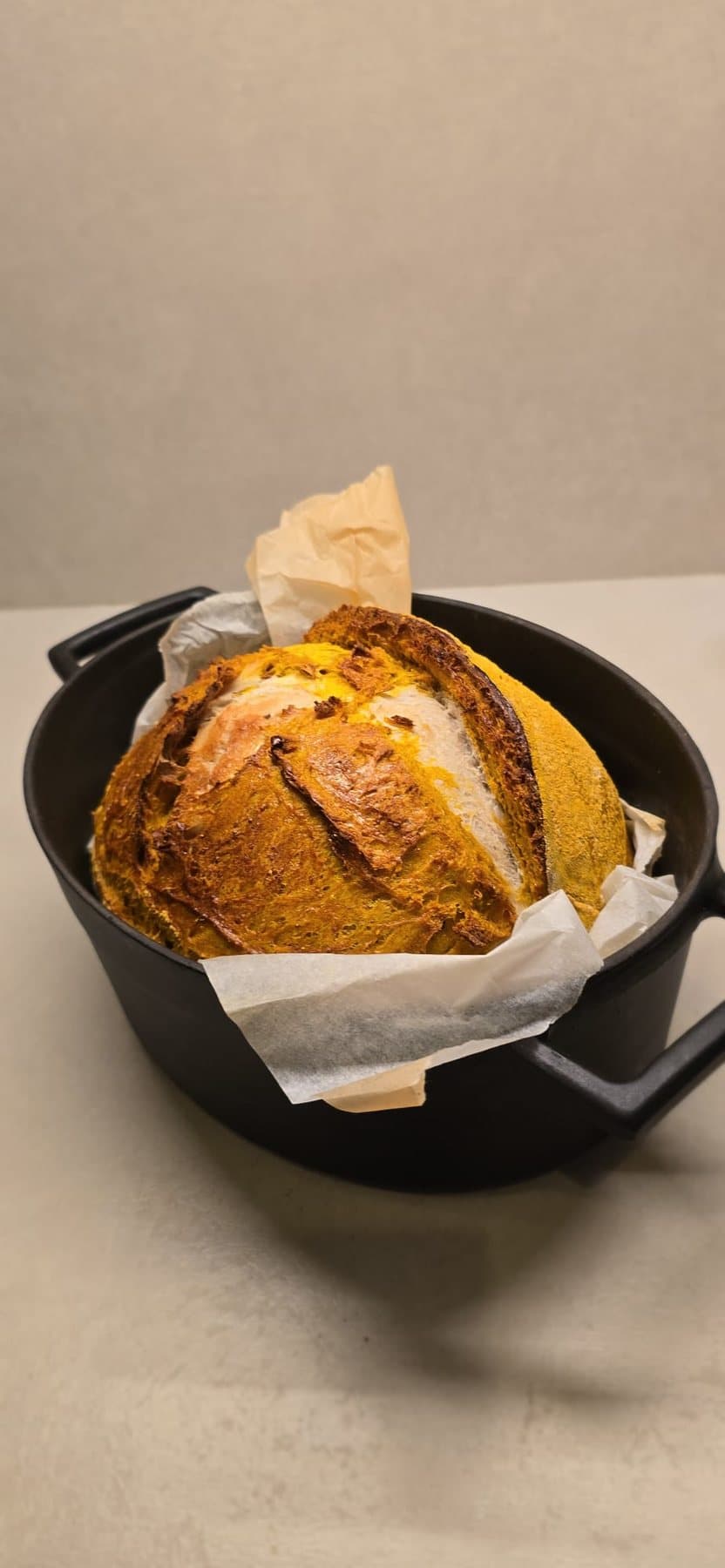 Un pain au curcuma, doré, dans sa cocotte en fonte, sur son papier