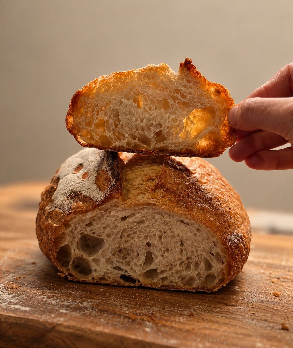 Une miche au levain, une tranche soulevée à la main au-dessus de la mie