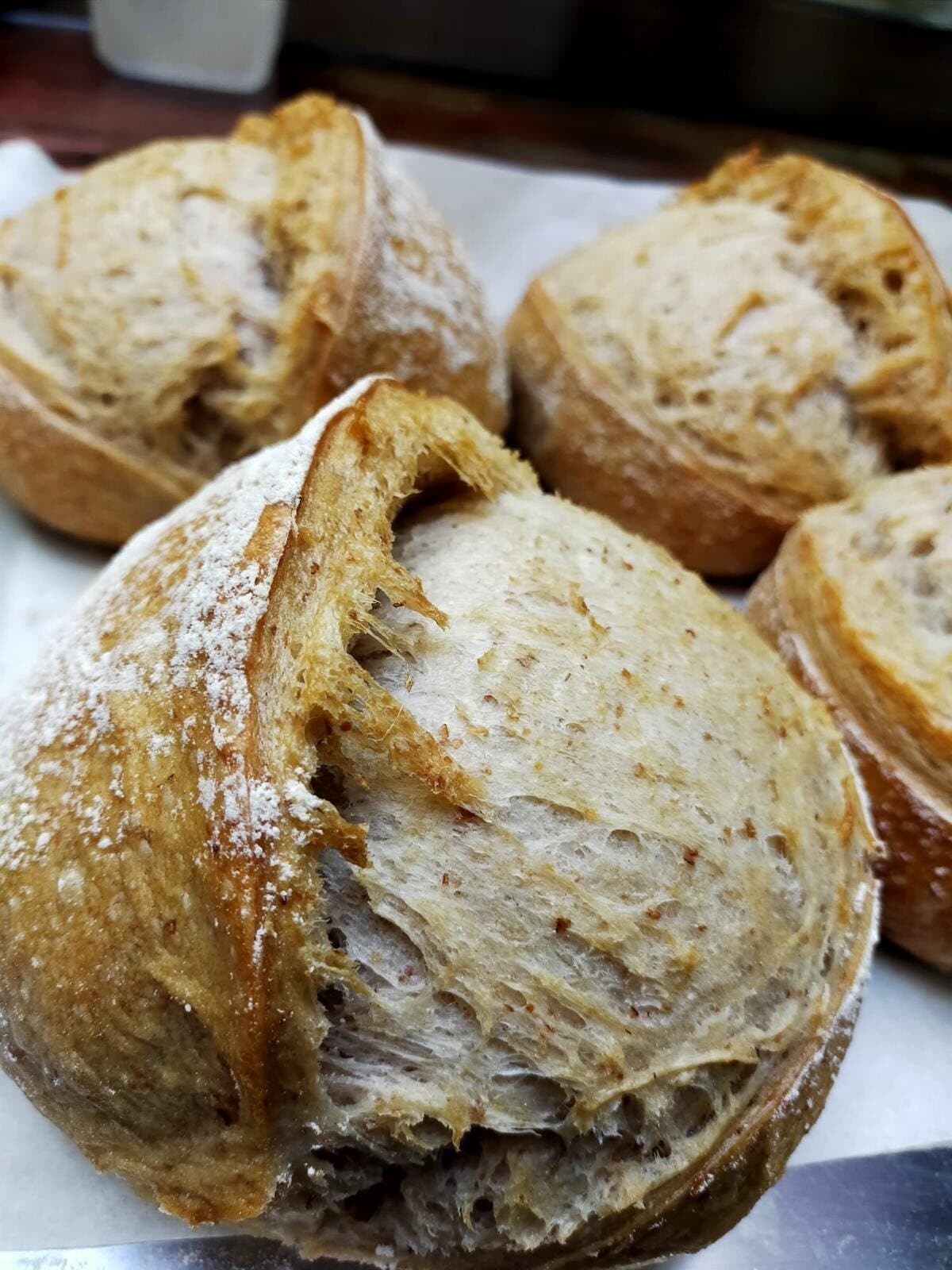 Des pains au levain en boule, la grigne largement ouverte, farinés
